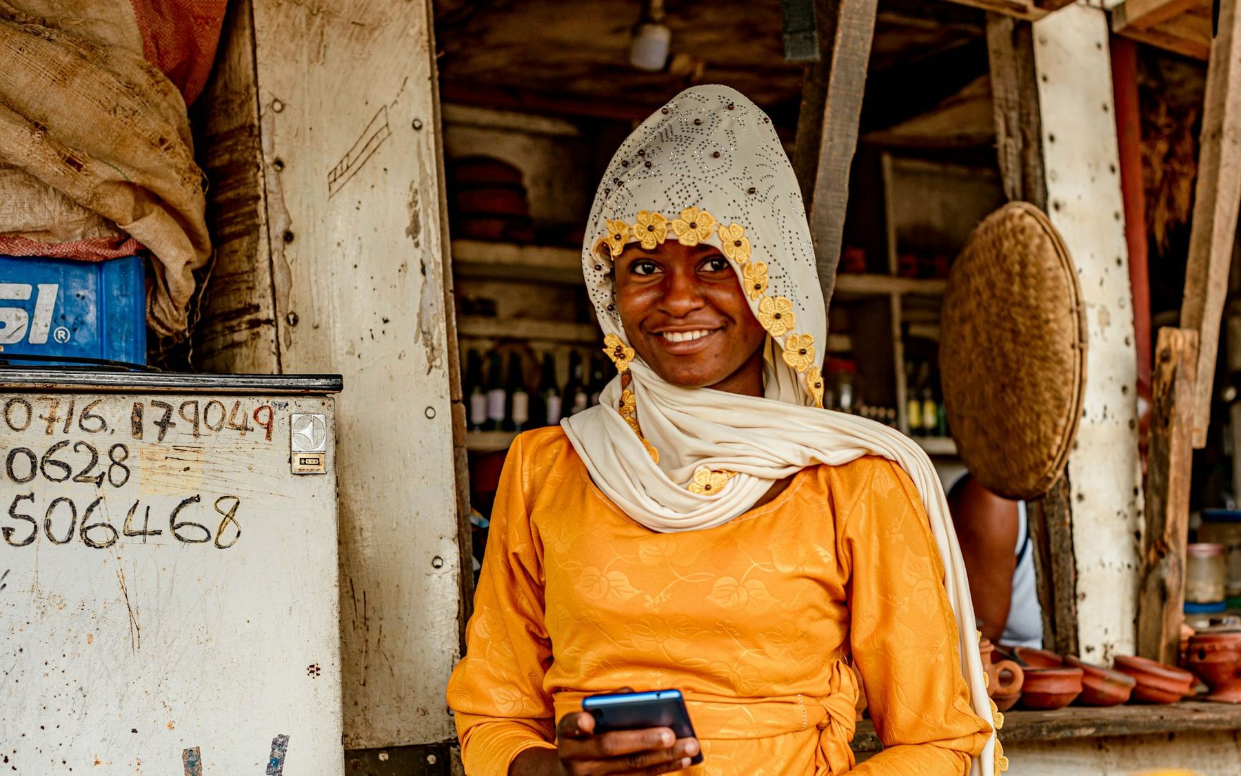 A smiling shop owner holding a phone in her store