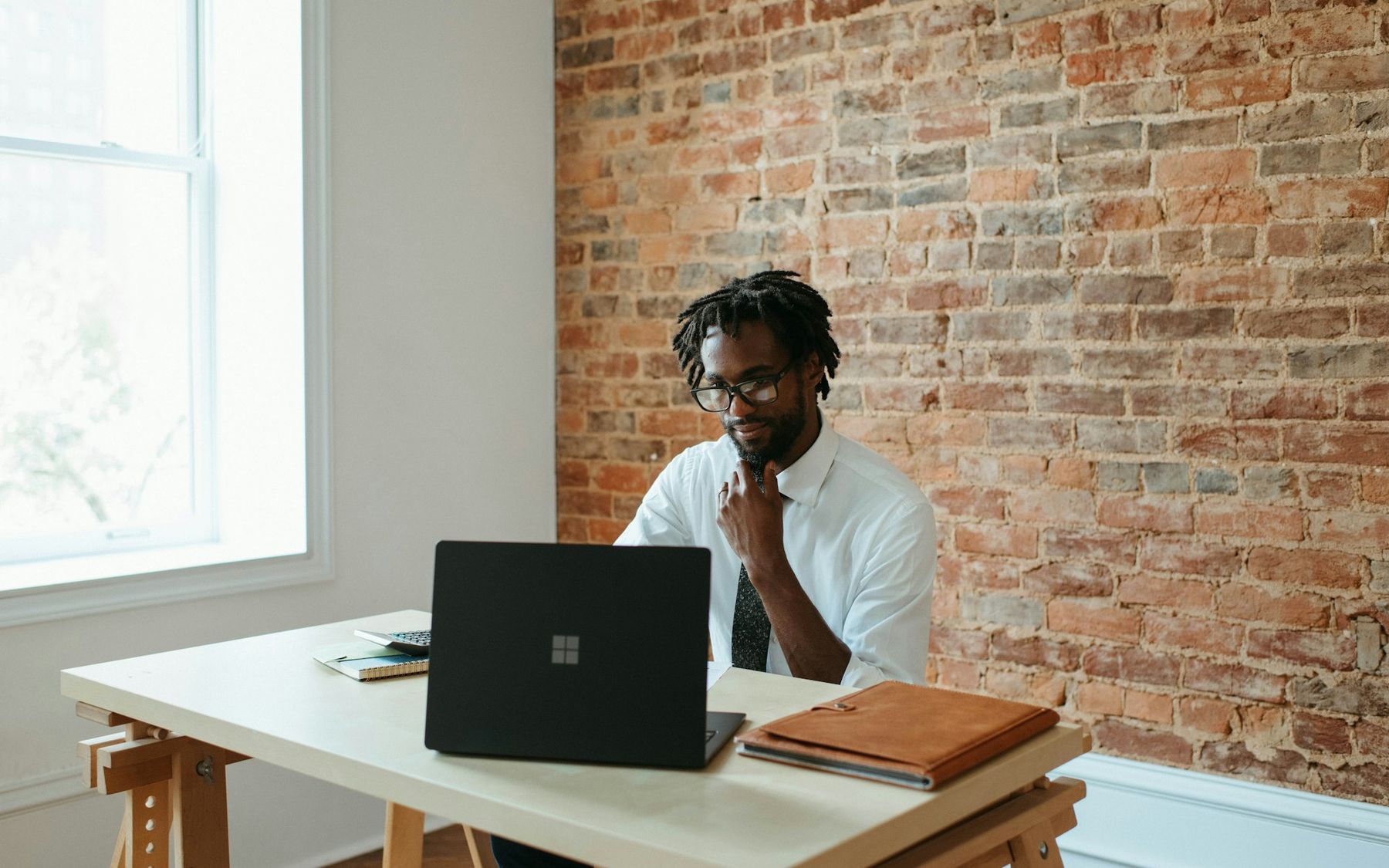 A business owner thinking while working on his laptop