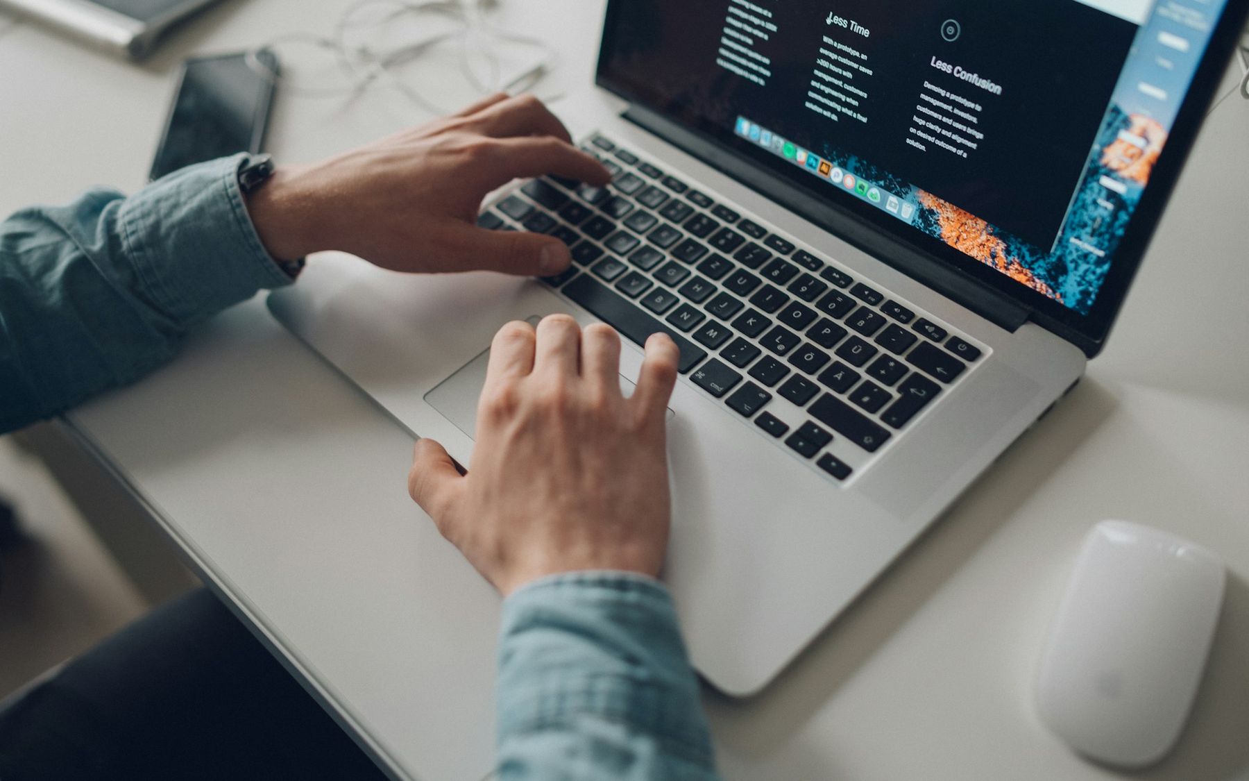 Hands typing on a laptop showing a website
